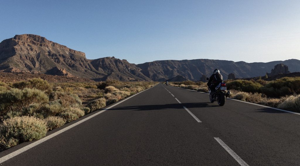 Motorcyclist riding a long road through the desert